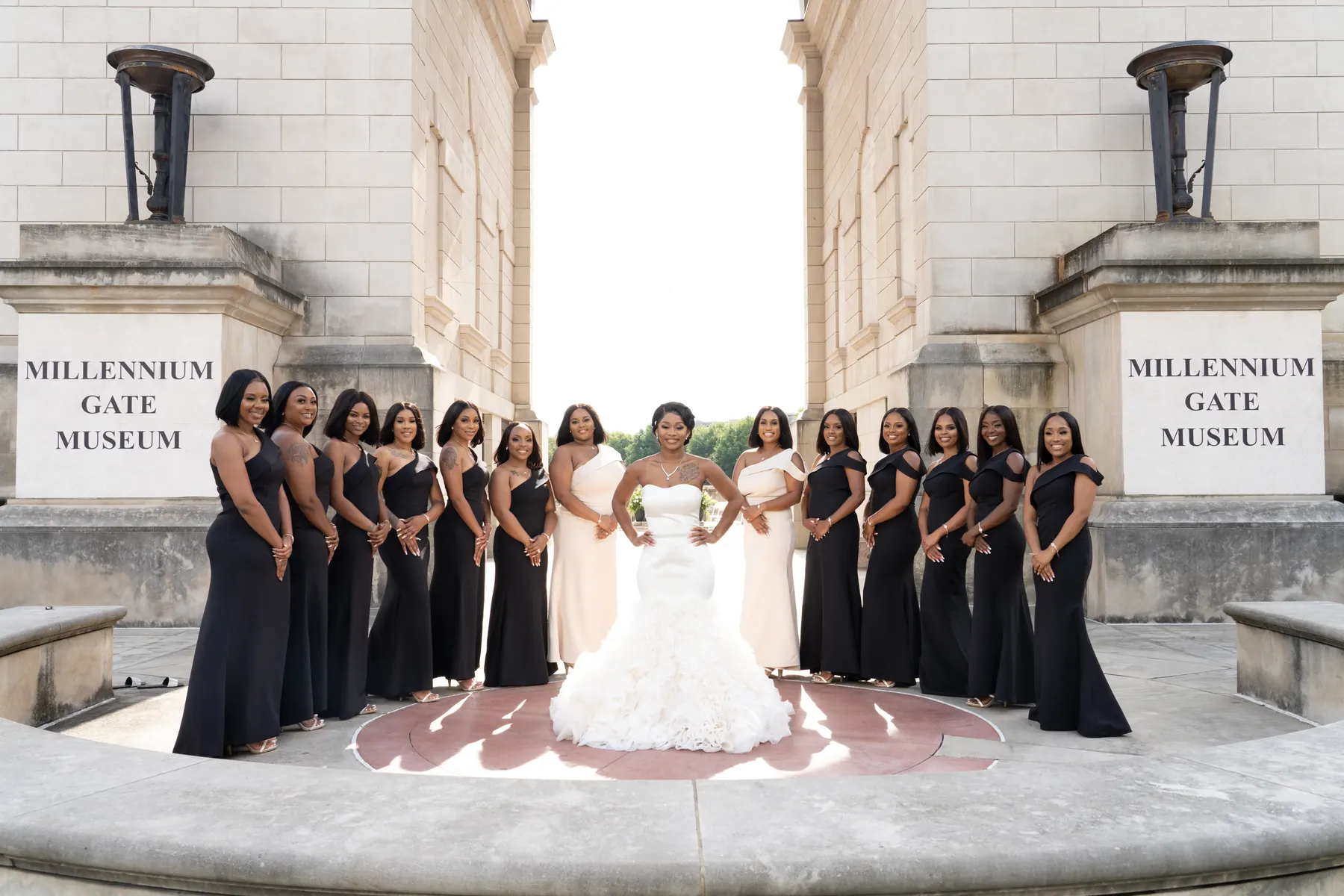 Bride surrounded by bridesmaids in black gowns on the steps of the Millennium Gate Museum in Atlanta