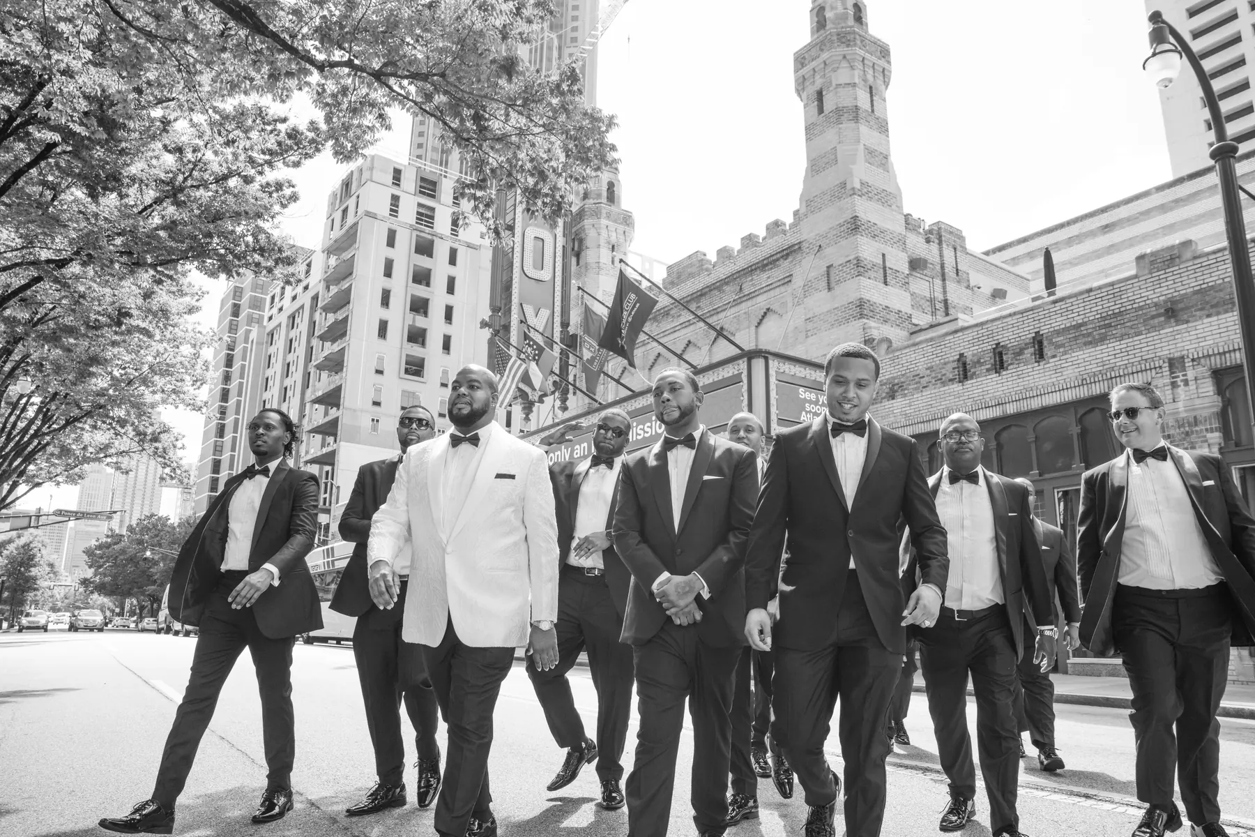 Black and white photograph of a groom and groomsmen walking confidently in front of an Atlanta church