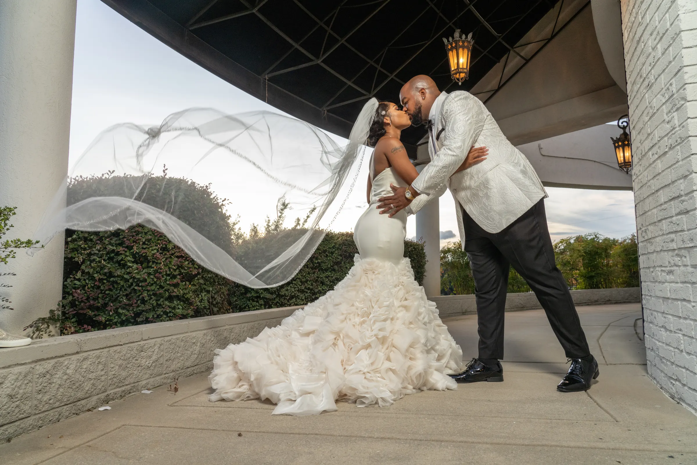 Groom kissing bride as her veil sweeps across the frame outside an Atlanta wedding venue