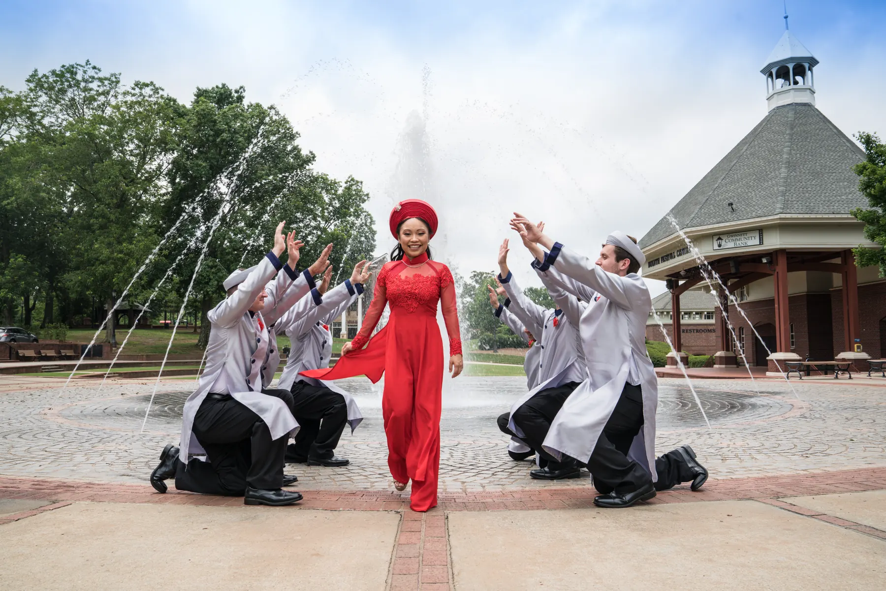 Wedding party in red, white, and silver striking playful poses in a courtyard